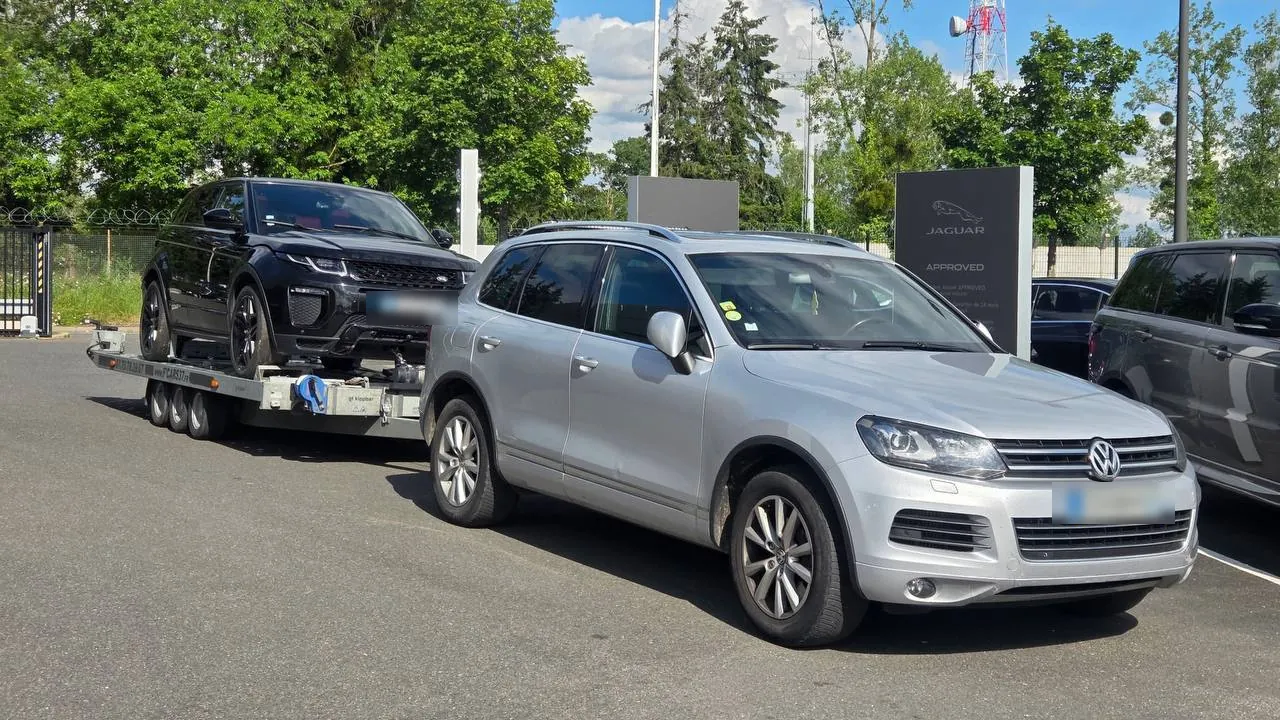 Range Rover Evoque livré sur plateau porte-voiture devant une concession automobile