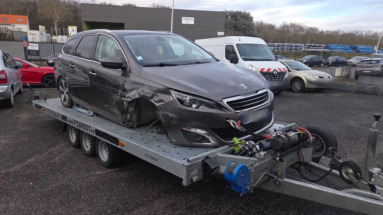 Enlèvement d'une Peugeot 308 accidentée sanglée sur plateau de dépannage