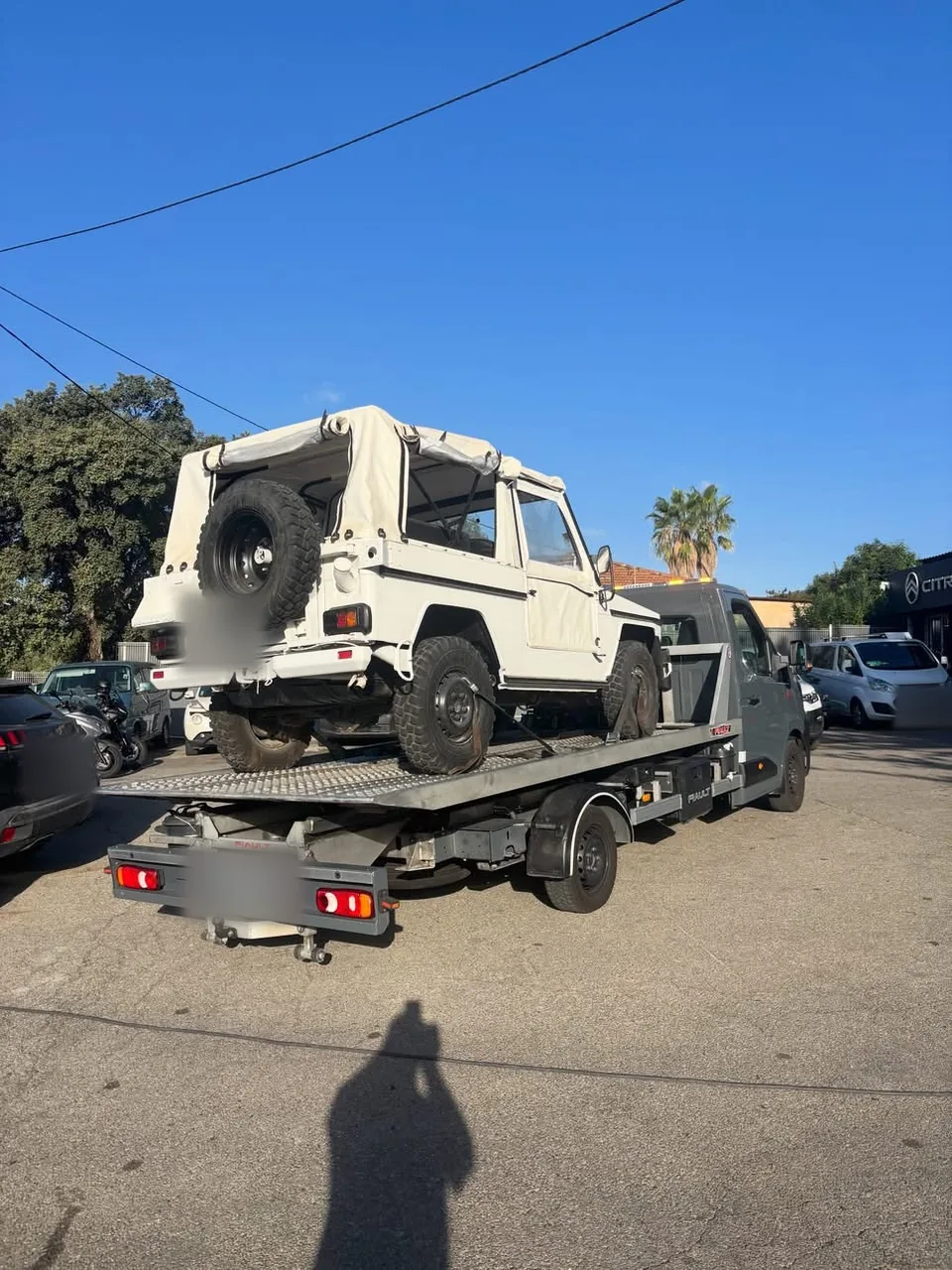 4x4 type Mercedes Classe G bâché chargé sur une dépanneuse plateau Renault Master