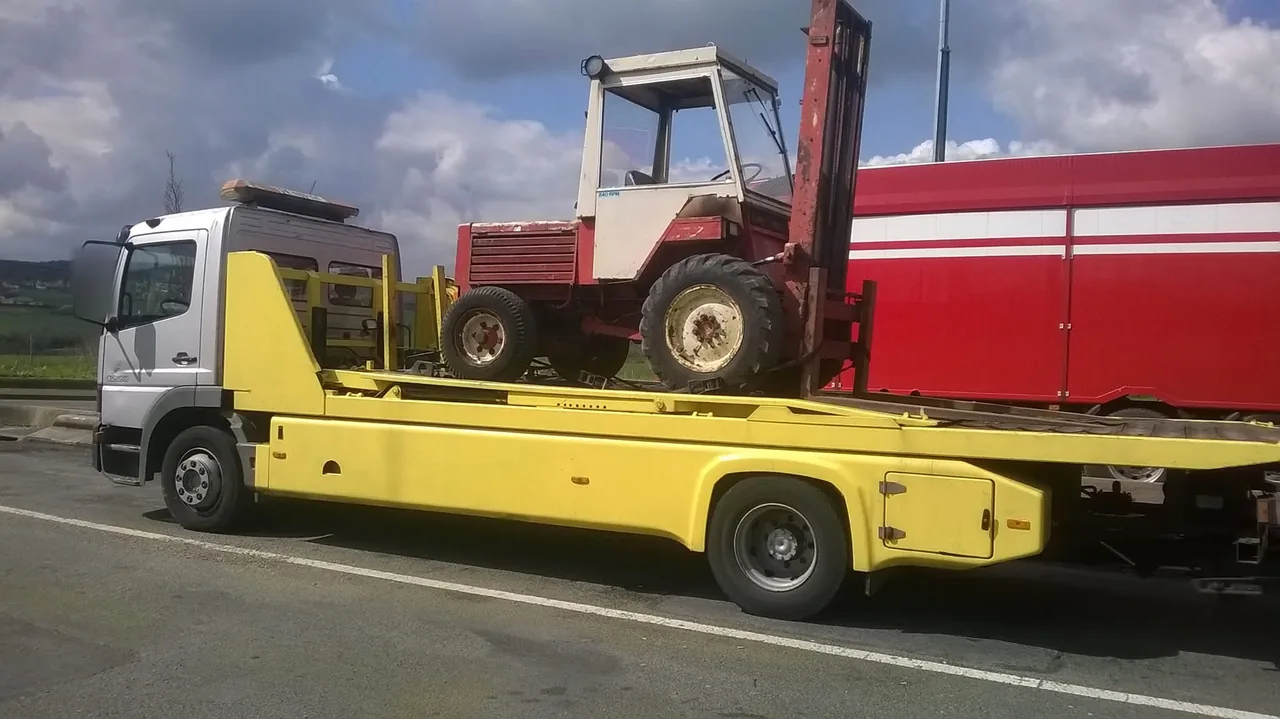 Chariot élévateur tout-terrain transporté sur un camion plateau jaune