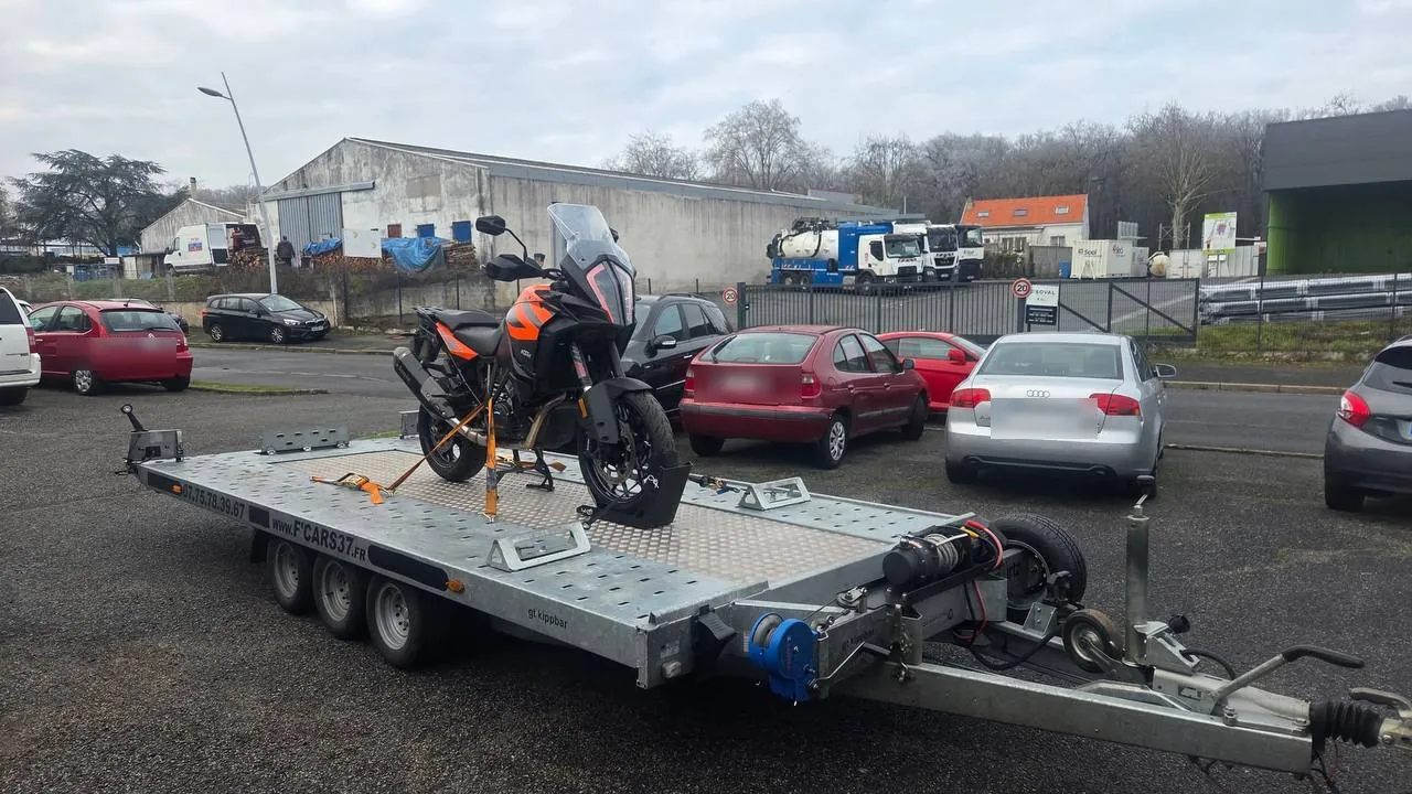 Moto KTM maxi-trail sanglée sur plateau porte-voiture pour transport